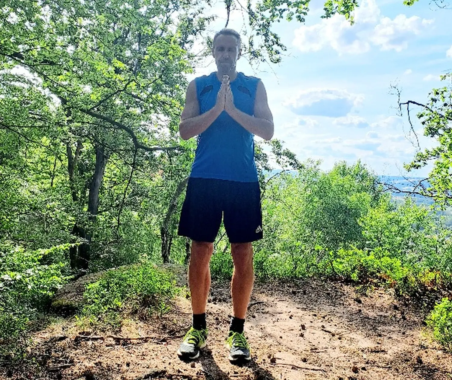 Joachim Roschel steht zur Meditation zwischen Waldbäumen